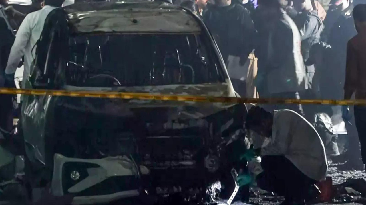 Delhi remains on high alert following a deadly blast near the Red Fort, with the NIA taking over the investigation. The explosion, linked to a ‘white-collar’ terror module, occurred hours after a major explosives seizure and arrests, raising suspicions of a premature detonation under pressure.  NEW DELHI: More than a day after the deadly blast that rocked the capital, Delhi remains on high alert as investigators piece together the chain of events that led to the explosion near the Red Fort, killing at least 12 people and injuring several others. The slow-moving Hyundai i20 erupted at a traffic signal on Subhash Marg, close to Gate No. 1 of the Red Fort Metro Station, setting nearby vehicles ablaze and sending panic across the historic quarter. Officials said the impact was so severe that a mutilated body was recovered from the mangled remains of the car.The National Investigation Agency (NIA) has formally taken over the case, after a review chaired by Union home minister Amit Shah. According to PTI, the blast came hours after eight people were arrested in Faridabad and 2,900 kg of explosives were seized from what officials described as a “white-collar” interstate terror module linked to Jaish-e-Mohammed and Ansar Ghazwat-ul-Hind. Preliminary security assessments suggest the explosion could have been accidental or triggered under panic as the terror network came under pressure following widespread raids.As investigators hunt for answers, the national capital has been placed on high alert. CCTV review teams have been deployed across Red Fort and adjoining corridors, while the city’s airports, bus terminals and railway stations have been placed under heavy security. Meanwhile, distraught families from Delhi, Uttar Pradesh and other states gathered at LNJP Hospital, waiting anxiously for identification of bodies and news of missing relatives.NIA takes over the probe; Centre calls it a terror-linked blastAccording to PTI, the investigation has been officially transferred to the National Investigation Agency after Home Minister Amit Shah held review meetings. The NIA will examine all aspects, including materials used, possible handlers, links to the busted Faridabad module, and whether the explosion was intentional or accidental. Delhi Police has also lodged a case under the Unlawful Activities (Prevention) Act and the Explosives Act. Prime Minister Narendra Modi, speaking in Thimphu, said agencies would “get to the bottom of the conspiracy” and that perpetrators “will not be spared”. ANI reported that Home Minister Amit Shah has instructed agencies to hunt down every individual involved. Forensic Science Laboratory teams are matching samples from the car with recovered body parts, while multiple police teams are filtering CCTV footage from Red Fort and adjoining routes to identify the masked man seen driving the vehicle.CM Rekha Gupta announces compensationDelhi chief minister Rekha Gupta announced Rs 10 lakh ex-gratia for families of those killed, and Rs 5 lakh for those permanently disabled or seriously injured. She said the government would ensure quality treatment and stood firmly with affected families. Shah has ordered the NIA to submit its report at the earliest. Security in Delhi has been tightened dramatically, with barricades and checks at border entry points. Traffic police issued advisories and diverted routes near Red Fort, with commuters urged to avoid the area.Umar Nabi suspected to be the driver; DNA samples takenInvestigators have zeroed in on Dr Umar Nabi, a doctor from Lethpora in Pulwama, believed to have been driving the car during the blast, as per newsagency PTI. He is suspected to be one of the dead, and Jammu & Kashmir Police have collected a DNA sample from his mother to confirm identity. Umar is alleged to have been carrying ammonium nitrate-based explosives when the vehicle detonated. Officials told PTI that he may have panicked after the Faridabad terror module was busted and possibly triggered the blast prematurely. Umar worked as a faculty member in Faridabad and had reportedly been an introvert who kept to himself. Investigators suspect he was on the run after learning of the arrests in Faridabad and waited for nearly three hours in the Sunehri Masjid parking area before driving towards Red Fort.The ‘white-collar’ terror module and 2,900 kg of explosivesThe blast occurred just hours after security agencies arrested eight people, including three doctors, and seized 2,900 kg of bomb-making material. Authorities described the network as a “white-collar” module spanning Kashmir, Haryana and Uttar Pradesh, connected to Jaish-e-Mohammed and Ansar Ghazwat-ul-Hind. Investigators recovered 360 kg of ammonium nitrate from Al Falah University in Faridabad alone. The module allegedly stored explosives across multiple states, raising concern over how a sophisticated network managed to acquire and hide such quantities. Agencies said pan-India alerts and coordinated crackdowns may have forced suspects to act in desperation. Preliminary findings suggest the IED was not assembled properly; there was no crater and no shrapnel, indicating the bomb was premature and may have detonated accidentally.Role of doctors: Arrests include Shaheen Sayeed and Muzammil GanaieThree doctors were among those arrested, including Dr Muzammil Ganaie and Dr Shaheen Sayeed, both linked to Al Falah University, PTI reported. Investigators said Shaheen headed the Jamaat-ul-Mominat – the women’s recruitment wing of Jaish-e-Mohammed – and was allegedly in touch with a handler in Pakistan. PTI reported that Shaheen, originally from Lucknow, was divorced in 2015 and had been living alone. Officials believe she may have been indoctrinated during this period. Her father told reporters he was unaware of her activities and heard of the arrest only through the media. Umar, also connected to Al Falah, allegedly carried out the car blast fearing he would be caught like the others. PTI reported that a man named Tariq from Pulwama gave him the i20 vehicle and has now been arrested.CCTV shows masked man; car waited three hours before blastCCTV footage showed a masked man driving the i20. Investigators confirmed the car had been parked for nearly three hours in the Sunehri Masjid parking lot, during which Umar reportedly checked the internet for updates about the Faridabad arrests. After the blast, police shut the Red Fort Metro Station and sealed surrounding areas. Overnight searches were conducted at hotels and guest houses in Daryaganj and Paharganj. All vehicles entering Delhi are now being checked. At least four people were detained in Kashmir for questioning; two have been moved for joint interrogation by Delhi Police, NIA and intelligence agencies.Victims: everyday workers with families waiting at LNJP HospitalHeartbreaking scenes unfolded at LNJP Hospital, where families struggled to identify bodies or locate missing relatives. Among those killed was 32-year-old Dinesh Mishra from Shravasti, who worked at a printing press in Delhi. His father told PTI that Dinesh had returned home for Diwali and worked hard to educate his children. Another victim, Ashok Kumar from Amroha, and Delhi resident Amar Kataria were identified, while other bodies remain unidentified and are believed to be aged between 28 and 58. At least 20 people were injured; 12 from Delhi and the rest from states including Uttar Pradesh, Uttarakhand and Himachal Pradesh. A hospital worker told PTI the scenes were “gruesome”, with ambulances arriving through the night and family members pleading for information.Blast material: Ammonium nitrate, detonators, fuel oilPreliminary forensic findings suggest ammonium nitrate, fuel oil and detonators were used in the blast. The lack of shrapnel and absence of a crater signalled a flawed assembly or premature trigger. Officials told PTI typical suicide car attacks involve ramming targets, but this vehicle was moving slowly at a traffic signal. Investigators are looking at whether the IED was triggered manually or by accident as Umar fled after the arrests in Faridabad. Agencies are also probing storage sites across Delhi-NCR and Kashmir, and how the module acquired explosive material despite surveillance. Multiple raiding teams continue to recover digital devices, communication logs and CCTV footage.Faridabad connection and Al Falah University under scannerAl Falah University in Faridabad is central to the investigation. Two of the arrested doctors worked there, and 360 kg of ammonium nitrate was recovered from campus-linked premises. Investigators are probing whether the university was used for recruitment, logistics or storage.Capital on alertSince the blast, Delhi has been on high alert and security has intensified at airports, railway stations and interstate bus terminals. CCTV scanning teams have spread across Red Fort, Chandni Chowk, Sunehri Masjid and adjoining roads. Police are checking private and commercial vehicles, questioning suspicious travellers, and monitoring hotel bookings. The Red Fort remains cordoned off with metro access shut. Investigators are focused on cracking communication links, funding trails and encrypted channels used by the module, while agencies continue interrogations in Kashmir and Delhi.(With inputs from agencies)About the AuthorTOI News DeskThe TOI News Desk comprises a dedicated and tireless team of journalists who operate around the clock to deliver the most current and comprehensive news and updates to the readers of The Times of India worldwide. With an unwavering commitment to excellence in journalism, our team is at the forefront of gathering, verifying, and presenting breaking news, in-depth analysis, and insightful reports on a wide range of topics. The TOI News Desk is your trusted source for staying informed and connected to the ever-evolving global landscape, ensuring that our readers are equipped with the latest developments that matter most.”Read MoreEnd of ArticleFollow Us On Social MediaVideosMaha Gajraj Exercise: IAF Conducts Highway Landing Operations Near Barmer-Jalore Border12 Killed In Car Bomb Blast In Islamabad; PM Sharif Blames ‘India-Sponsored Terrorist Proxies”Hunt Down Every…’: Amit Shah Says Delhi Car Blast Culprits To Face ‘Full Wrath Of Agencies’Bihar Exit Polls 2025: Poll of Polls Show NDA Poised For Majority, MGB Trails, No Impact of JSP’Op Sindoor Taught Us…’: Army Chief Dwivedi On Role Of Modern Tech In Warfare At Cavalry Seminar‘We Love India’: Bhutan King Reaffirms Ties As PM Modi Unveils Connectivity, Energy BoostBangladesh Elections: Awami League, BNP Allege Lawlessness Under Yunus, Fear Violence In PollsIndia Tells UNSC To Enforce Zero-Tolerance On Terror Strictly Hours After Delhi Blast Kills Twelve’No Silver Medals In War’: CDS Chauhan Highlights India’s Technological Leap Amid Rising ThreatsLucknow Doctor Tasked By JeM To Form Women’s Terror Wing In India, Police Link To Delhi Blast Probe123PhotostoriesHow to choose a perfectly ripe avocado every time from the clues present on its skin8 Bollywood actresses who swear by ghee every morning and whyTop trending gold chain designs of 20256 courageous freedom fighters of the Indian independence struggle that remain unsung to date10 powerful baby boy names that reflect strength and courageSadhguru calls fenugreek or methi a miracle medicine, ‘If taken properly it can…”Feeling tired all the time? You might have a Vitamin B12 deficiency — Here are the warning signsHina Khan to Bhagyashree: 5 must-see celeb looks of the day trending nowBeetroot with chia seeds: A natural superfood combo for heart and gut healthCurbing the menace: 8 houseplants that fight air-pollutants123Hot PicksBihar Election CandidatesBihar Election ConstituenciesBihar Election 2025Gold rate todaySilver rate todayPublic Holidays NovemberBank Holidays NovemberTop TrendingRed Fort blastJamie DimonDelhi Car BlastWWE Raw HighlightsMichael Willis Cause of DeathCade CunninghamStephen CurryCandace OwensMLB Trade RumorsDennis Hildeby